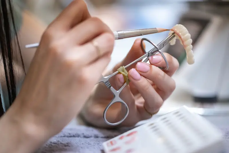 Mâini care lucrează la o lucrare dentară